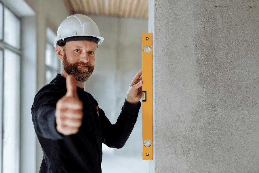 Survival card manufacturing: man in hard hat doing a thumbs up while holding a spirit level