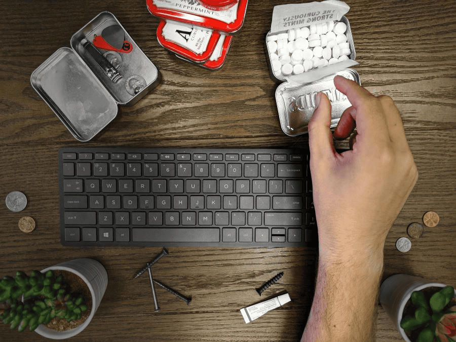 Survival card suppliers: male hand and Altoids tins on wooden office desk