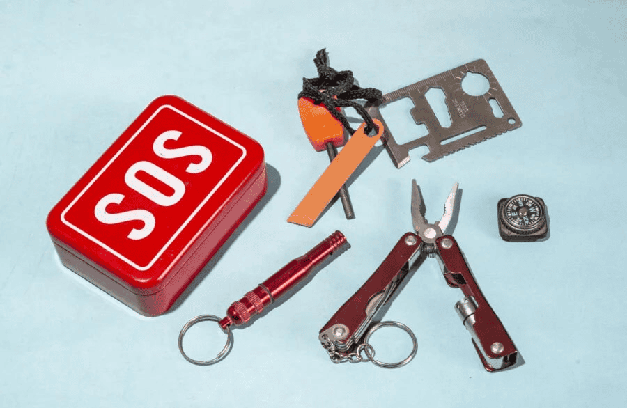 Survival card factory: emergency kit with survival card and other tools on a blue surface.