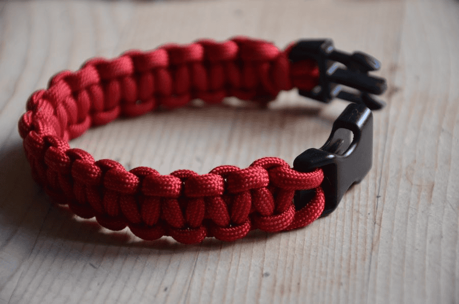 Paracord manufacturer: red paracord survival bracelet on a wooden surface.