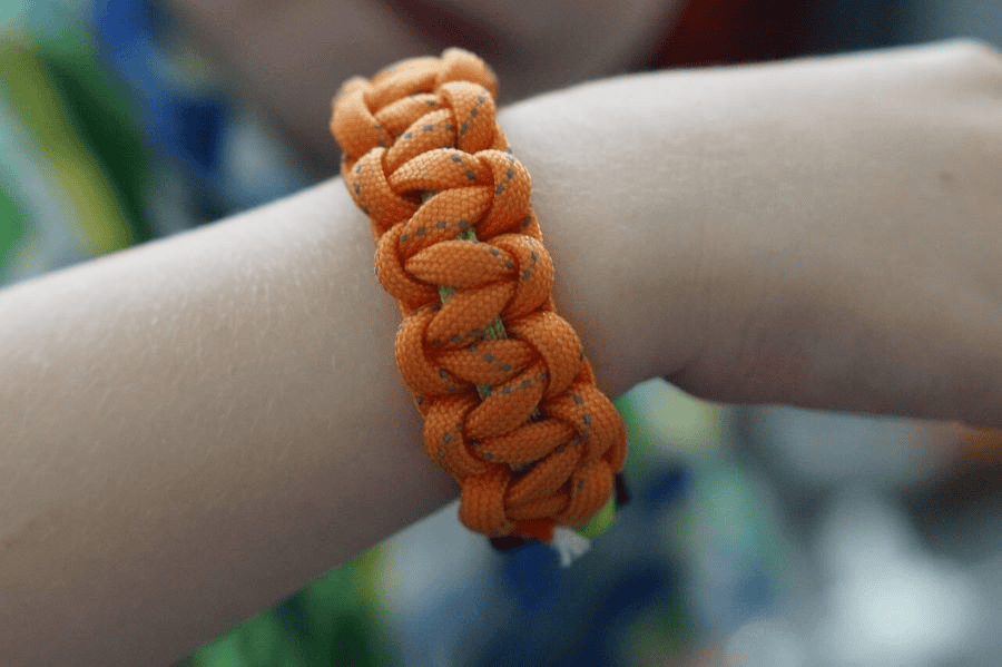 Paracord wholesale: A child wearing an orange paracord bracelet.