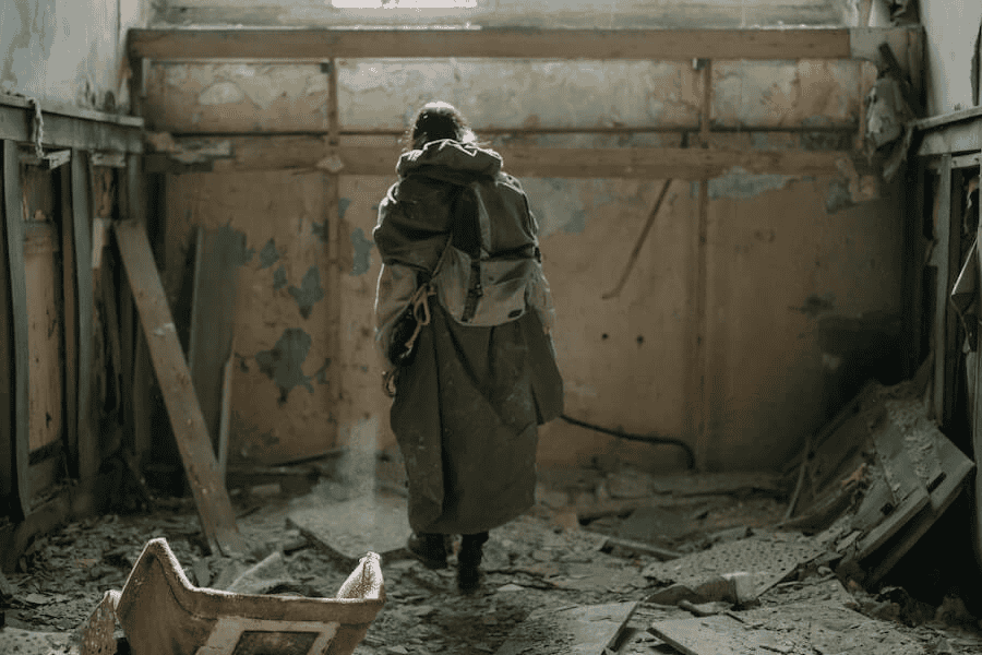 Paracord manufacturer: Person in long brown coat standing inside the ruins of an abandoned building.