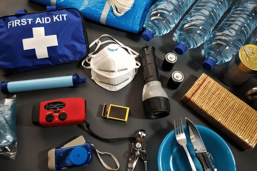 Paracord manufacturing: First aid and survival kits on black table.