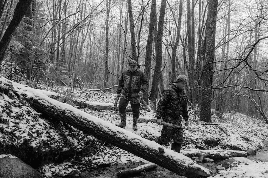 Paracord manufacturer: Two men walking in the woods and holding rifles.