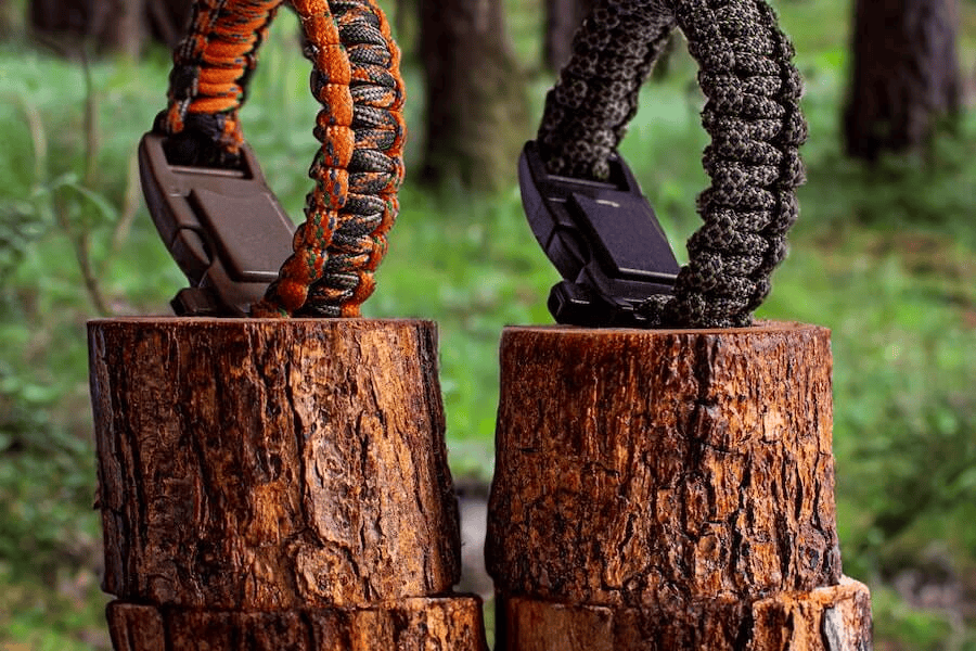 What Is the Survival Cord? A Comprehensive Guide to Its Benefits, Uses, and Paracord Manufacturer 2 Paracord factory: Two survival paracord bracelets on tree stumps in the forest.
